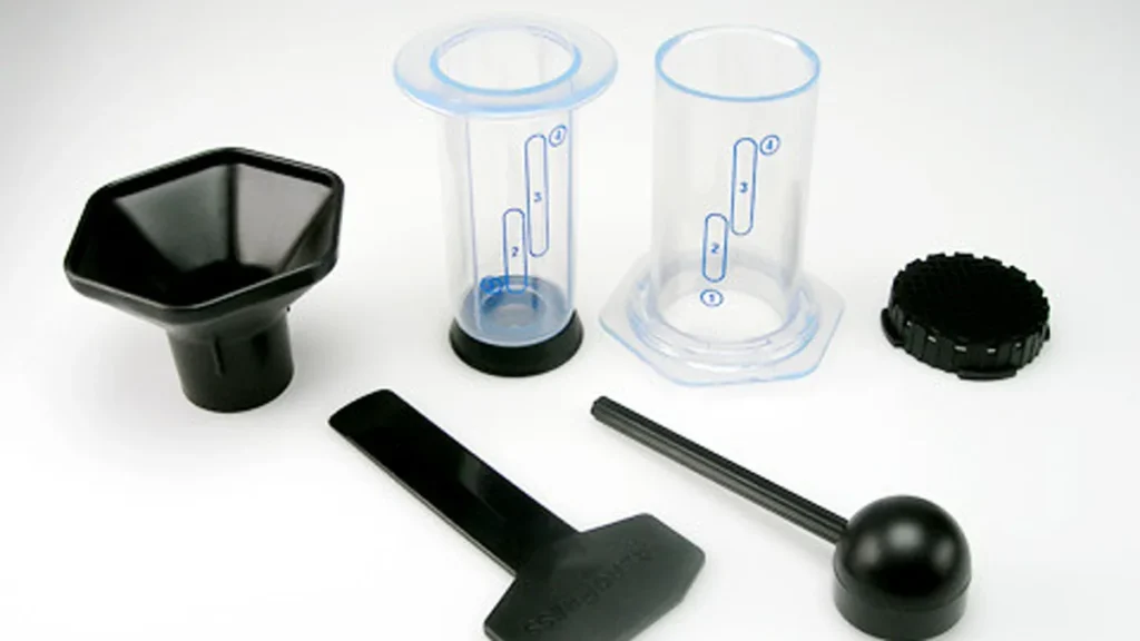 Barista hands pressing down the plunger of an AeroPress coffee maker into a sturdy ceramic mug