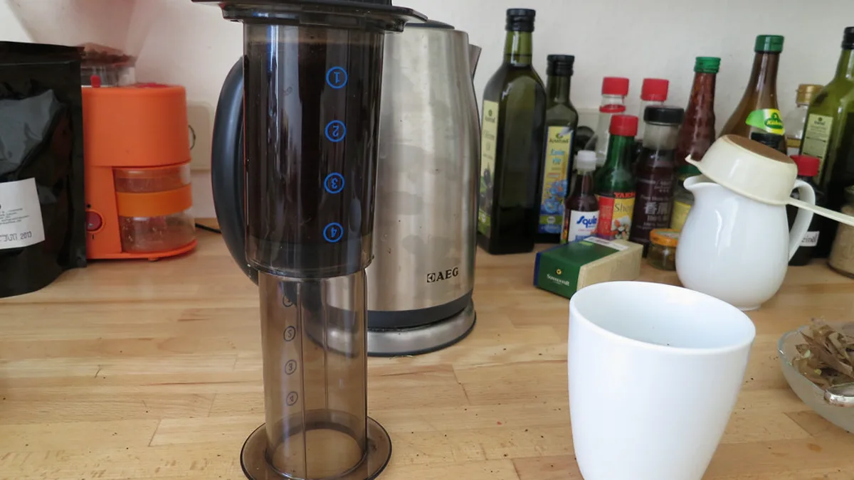 An AeroPress brewer standing in the inverted position on a kitchen table during a two-minute immersion brew
