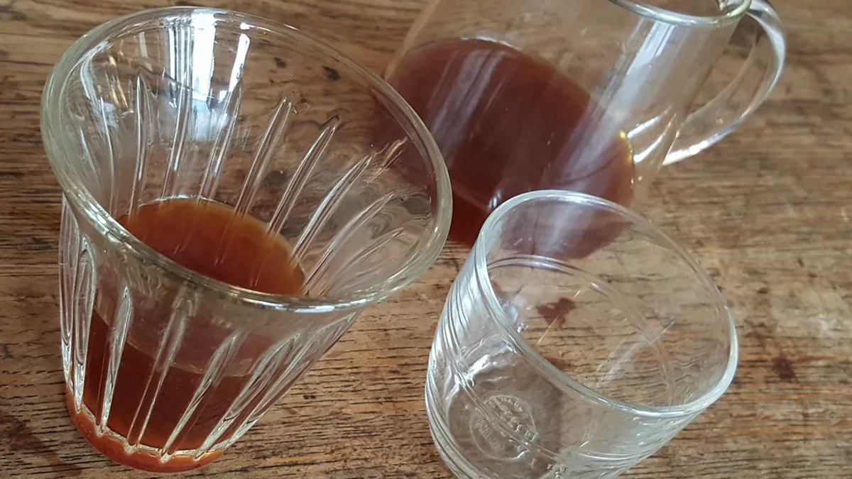 A freshly pressed, translucent amber cup of AeroPress specialty coffee resting beside the disassembled plastic brewer