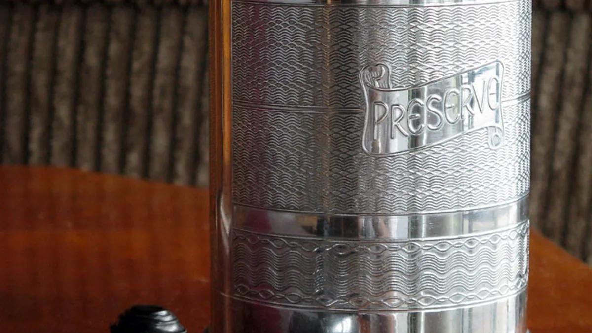 Close-up of roasted coffee beans showing light surface lipid sheen in an opaque ceramic storage container