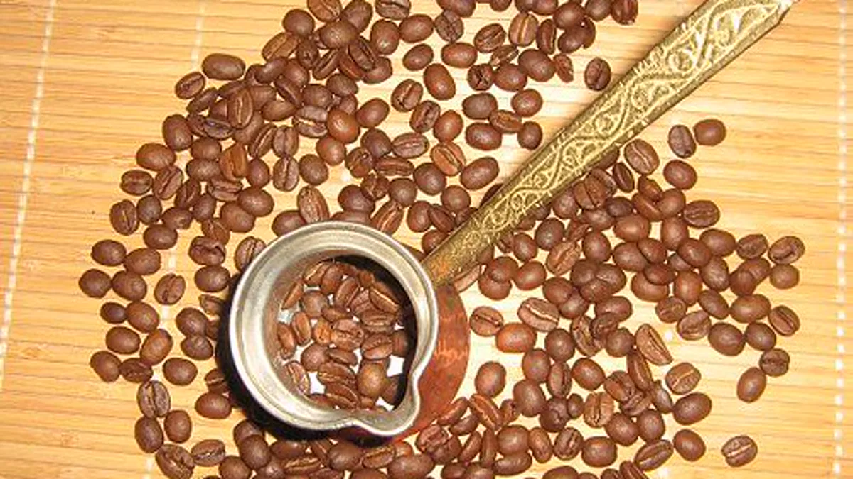 A barista pouring fresh whole coffee beans from a sealed valve bag into an airtight glass jar