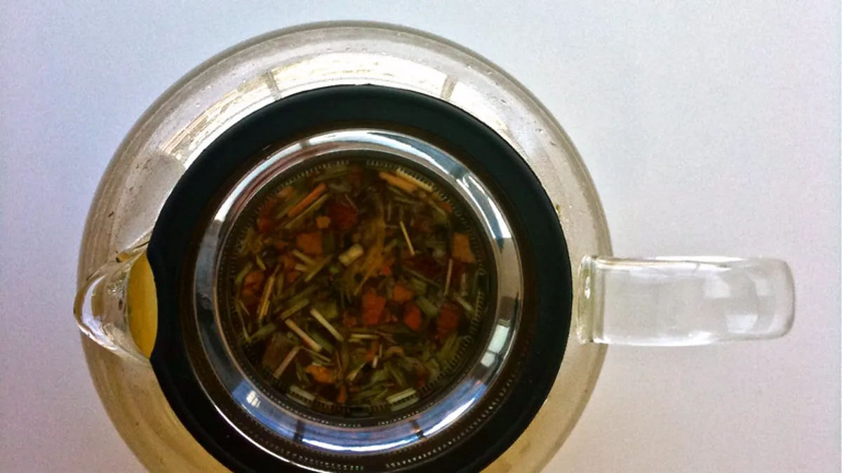 Hot water pouring into a clear glass teapot allowing sparkling whole tea leaves to expand and dance freely